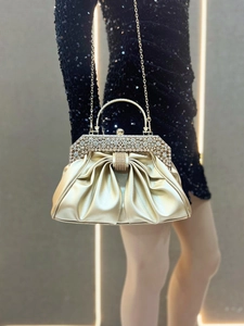 Detail of gold pleated evening clutch bag with sparkling rhinestone frame and metal chain