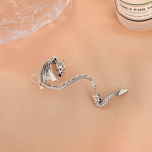Silver dragon ear cuff with detailed scale texture in punk style on warm orange backdrop