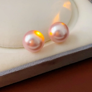 Macro view of high-luster pink round pearls on white velvet jewelry display stand