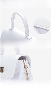 Detail of white leather bag featuring quilted texture and gold metal chain strap