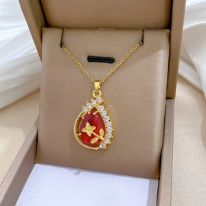 Macro shot of gold teardrop necklace with red gemstone and diamonds in a jewelry box