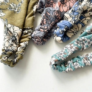 Flat lay detail of assorted floral pattern cotton headscarves in olive and turquoise