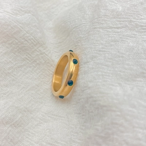 Vue macro d'une bague en acier titane plaqué or 18K sertie de pierres vert foncé