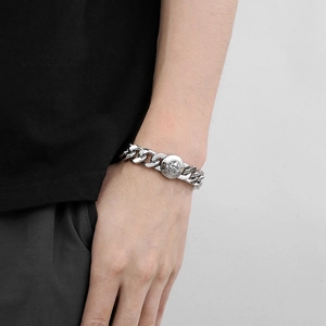 Polished silver Cuban chain bracelet featuring a distinctive embossed skull round clasp