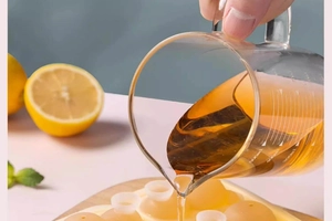 Detail of pouring liquid into sphere ice molds using a 500ml glass measuring cup