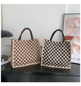 Detail of checkered burlap tote bags with round handles on a dark wood surface