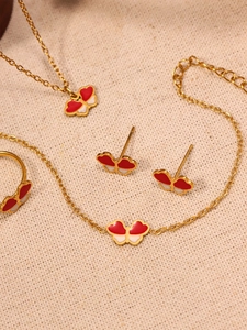 Vue détaillée de l'ensemble bijoux papillon en émail rouge et blanc sur chaîne dorée