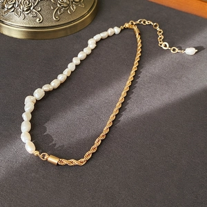 Détail du collier de perles baroques et chaîne torsadée dorée sur surface sombre
