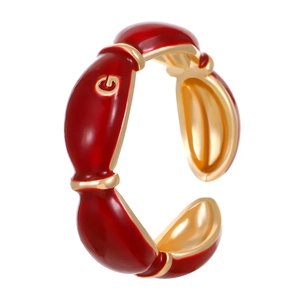 Detail of red enamel C-shape cuff bracelet with gold G letter and metallic accents