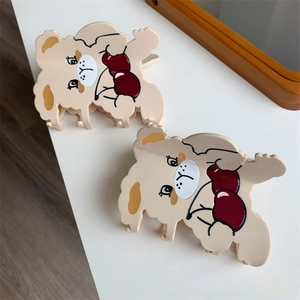 Close-up of two cute bear-shaped hair claws in cream and red plastic material