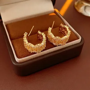 Luxury gold C-shaped hoop earrings with micro-set zircons displayed in a jewelry box