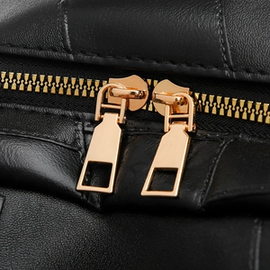 Detailed macro view of black lychee leather bag featuring premium dual gold metal zippers