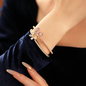 Bracelet papillon doré avec zircon violet et fleur en cristal au poignet de femme