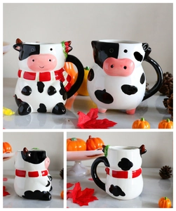Detail view of 3D cow-shaped ceramic coffee mugs with autumn decorations and red scarf accent