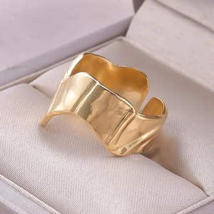 Detail of gold irregular ripple open ring with hammered texture in a beige jewelry box