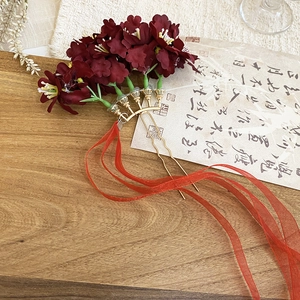 Detail of red fabric flower hair pin with long ribbons and golden U-shaped metal pins