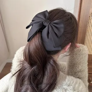 Detailed back view of a large black satin bow banana clip holding a half-up ponytail hairstyle