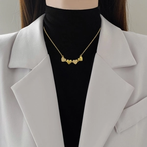 Gold titanium steel necklace featuring four interlocking heart pendants on a model