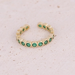 Detailed macro view of adjustable gold ring with micro-pave green circular gemstones
