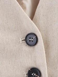 Detail of beige linen vest featuring V-neckline and black four-hole buttons with texture