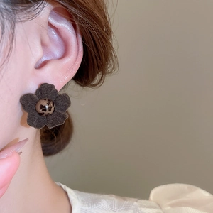 Detail of vintage fabric flower earring with leopard print center on a female model