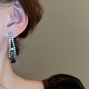 Close-up of elegant black crystal teardrop fringe earrings worn by a model