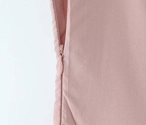 Détail de la fermeture éclair invisible sur une robe de princesse rose poudré plissée