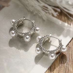 Silver wide hoop earrings with white pearls and beaded edges on elegant white background