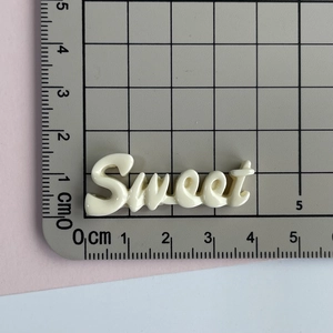Gros plan d'un accessoire Sweet en résine crème sur tapis de découpe avec mesures