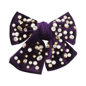 Dettaglio di una clip per capelli con fiocco viola decorata con perle e strass di lusso