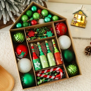 Assorted red and green Christmas ornaments in a house-shaped kraft box on a white rug