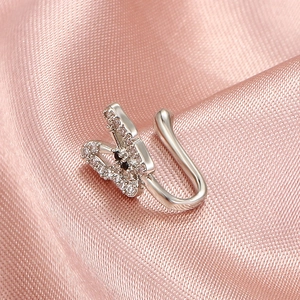 Detailed view of a silver butterfly non-piercing nose clip with diamonds on pink silk