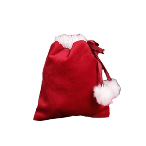 Red velvet Christmas drawstring gift bag with white pom-poms on a clean white background