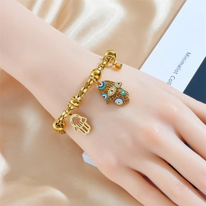 Golden Hamsa Hand bracelet with blue Evil Eye pendant on beige silk background