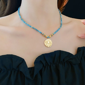 Close-up of ethnic beaded necklace with golden eye pendant worn by a model