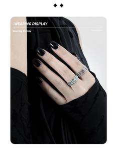 Detailed view of hollow design silver rings and mint green textured ring on model hand