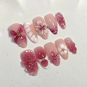 Macro view of 3D floral almond press-on nails with pink gradients and pearl accents