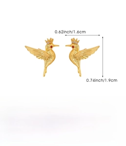 Detail view of golden hummingbird earrings with red crystal eyes and crown accents