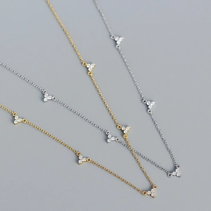 Détail de colliers S925 or et argent avec pendentifs en trèfle sertis de zircons
