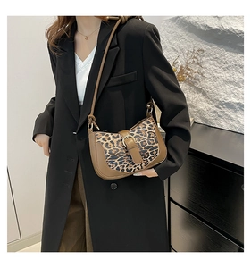 Close-up of leopard print shoulder bag with brown leather trim worn by a model in a suit