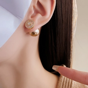 Detail view of gold-plated pearl and zircon earrings worn by a model for size and style reference