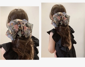 Détail d'une pince à cheveux fleurie en mousseline montrant la texture sur les cheveux
