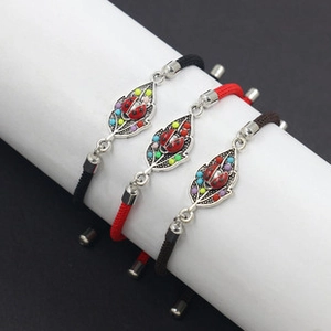 Detailed view of woven bracelets with ladybug and leaf charms on white display