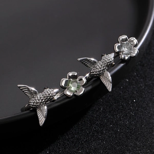 Macro shot of silver hummingbird ring with green stones and floral vintage details