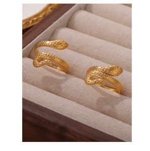 Close-up of gold-plated snake rings with intricate scale textures in a jewelry box