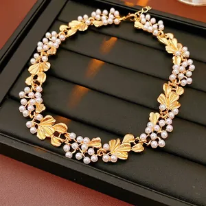 Vintage flower pearl necklace with golden metal leaves set on a black jewelry stand