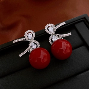 Detailed macro view of red spherical drop earrings with sparkling rhinestone bow accents
