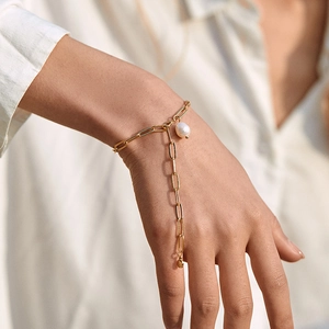 Gold paperclip chain bracelet with baroque pearl charm on minimalist white clothing