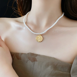 Détail du pendentif œil porte-bonheur plaqué or avec zircons sur collier de perles