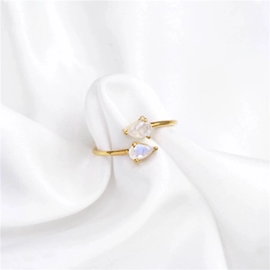 Close-up of gold open ring with pear-cut transparent gemstones on white silk